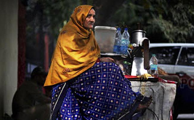 A poor elderly woman vendor sits on her cart as she waits for customers in New Delhi. India will pay billions of dollars in social welfare money directly to its poo. Photo: AP