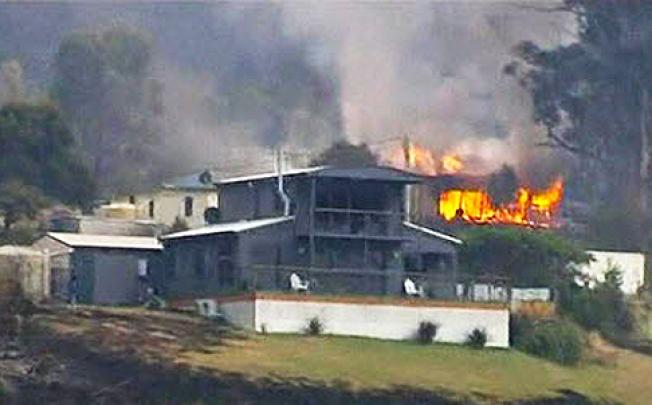 A house burns in the Tasmanian town of Dunalley on Saturday as bush fires rage in Australia. Photo: Reuters