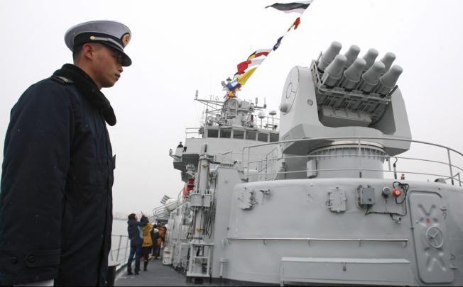 A member of China's People Liberation Army (PLA) stands at guard on the missile destroyer 'Qingdao'. Photo: EPA