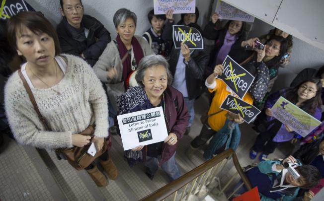 Participants hold placards and chant slogans as they take part in a march against violence towards women in a staircase leading to the India consulate in Hong Kong. Photo: EPA