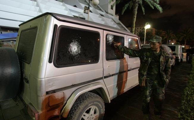 A security guard points to the bullet impacts on the bulletproof vehicle of Italy's consul to Benghazi. Photo: AFP