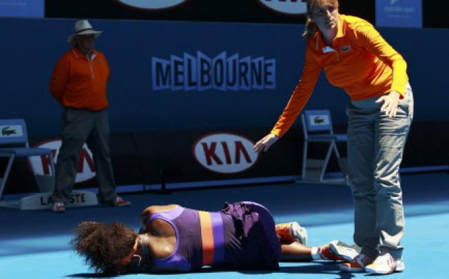 An offical stands over Serena Williams after she fell over during the women's singles match at the Australian Open tennis tournament in Melbourne on Tuesday. Photo: Reuters 