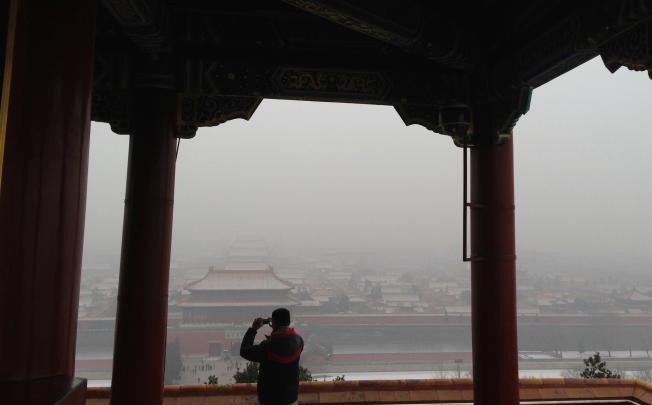 A tourist takes photos of the Forbidden City in smog in Beijing on Jan 23, 2013. Photo by Simon Song