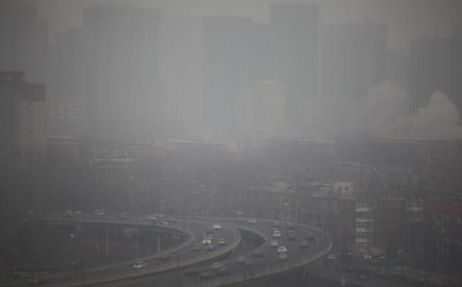 Cars run on an elevated road as buildings in the background are covered in haze, Beijing. Photo: EPA