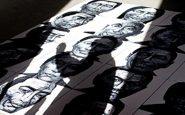 A Beijing artist lays out his portraits of Tibetans who have self-immolated. Photo: AP