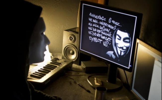 A masked hacker hacks the French presidential Elysee Palace website. Photo: AFP