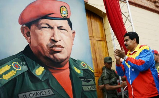 Venezuelan Vice President Nicolas Maduro (R) looks at a portrait of Venezuelan President Hugo Chavez. Photo: AFP