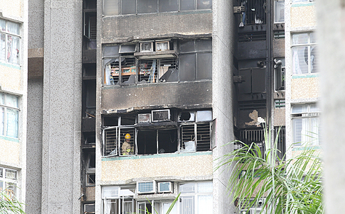 Firemen inspect the ninth-floor Cypress House flat in the Kwong Yuen housing estate in Sha Tin where a fire caused the death of a woman and injured four people early on Friday morning. Photo: Edward Wong