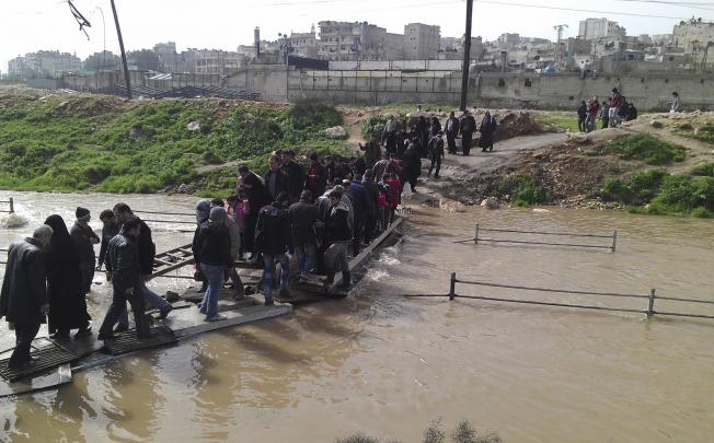 People cross a makeshift bridge between the Sheikh Maksoud and Bustan al-Basha districts of Aleppo. Photo: Reuters