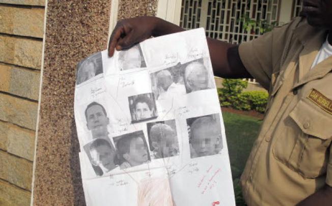 A security guard shows photos of Tanguy Moulin-Fournier and wife Albane (centre) and their four children, kidnapped this month while visiting the Waza National Park.. Photo: AFP