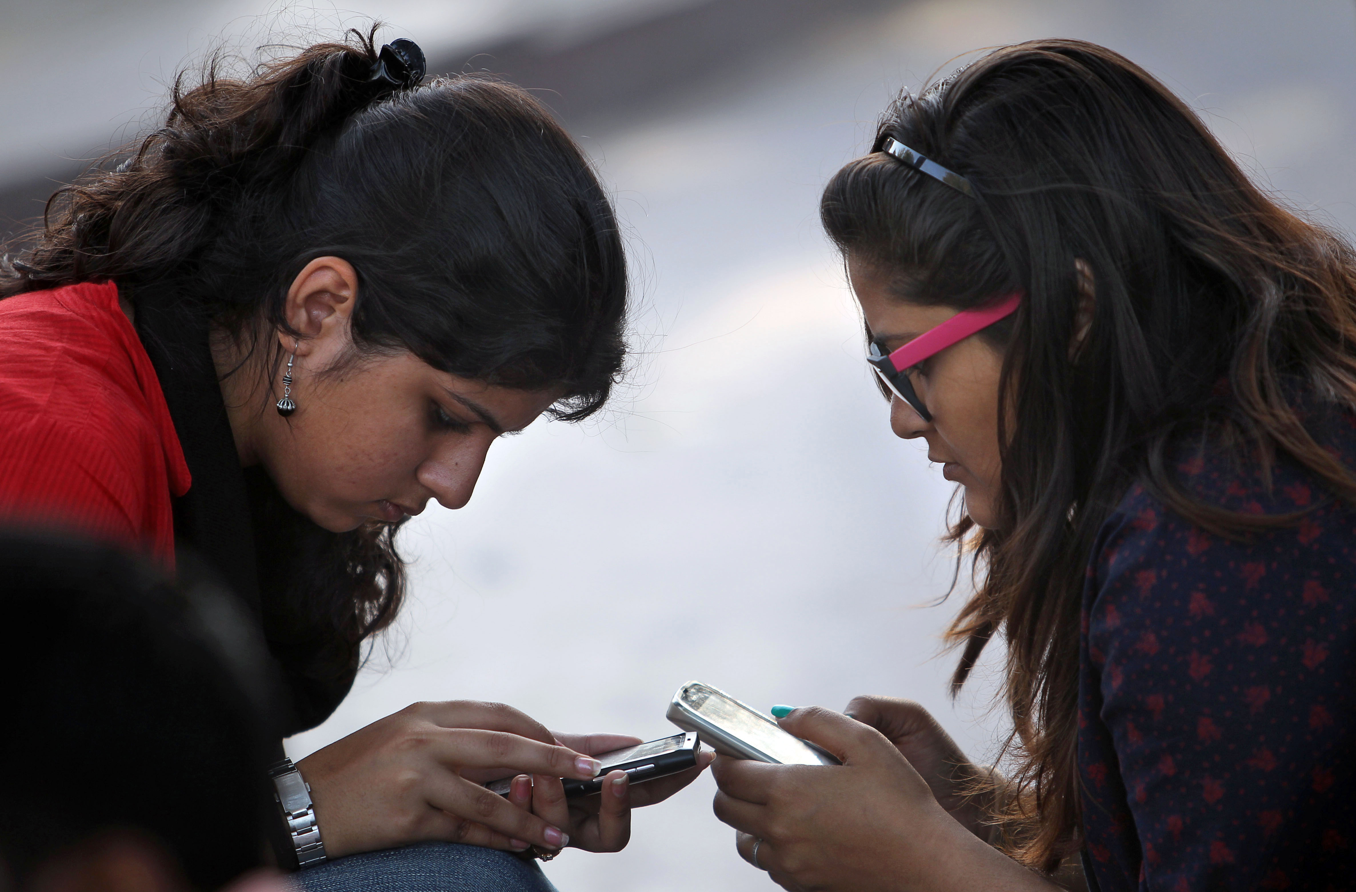 Indian girls engage with their mobile phones in New Delhi, India. Photo: AP