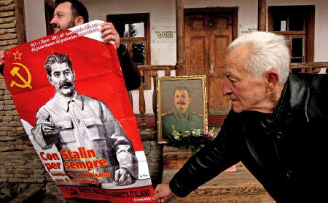 Two Georgian men hold a portrait of Soviet dictator Joseph Stalin as they mark the 60th anniversary of Stalin's death. Photo: EPA