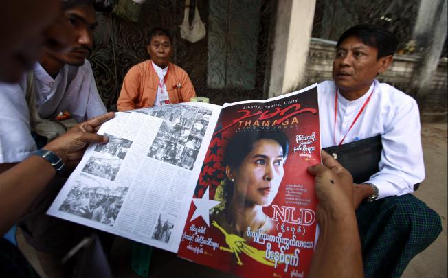 Delegates read a local news journal containing news about the NLD's congress before attending the day's session of the congress in Yangon. Photo: Reuters