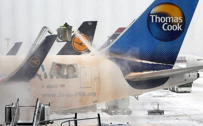 Airport workers de-ice a plane on the snow-covered tarmac of Frankfurt airport. Photo: AFP