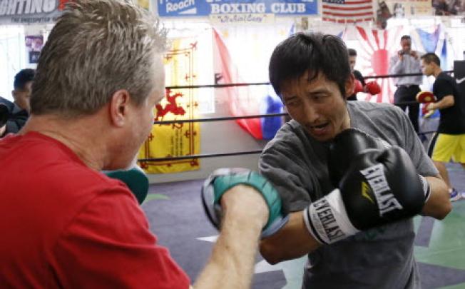 Two-time Olympic gold medalist and three-time world amateur boxing champion Zou Shiming of China works out with trainer Freddie Roach (left). Photo: Reuters