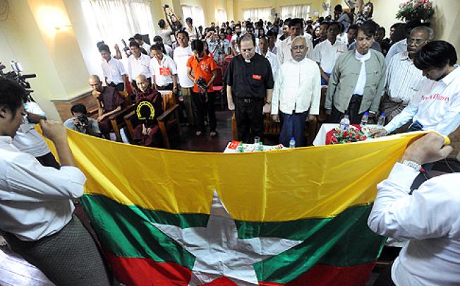 Myanmar people from different religions pay their respect in front of Myanmar's national flag during a multi-confessional peace ceremony in Yangon on Thursday. Photo: AFP