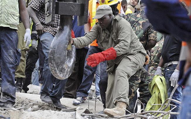 A rescuer guides the hook of a crane to remove rubble from a collapsed building in Dar es Salaam. Photo: AP