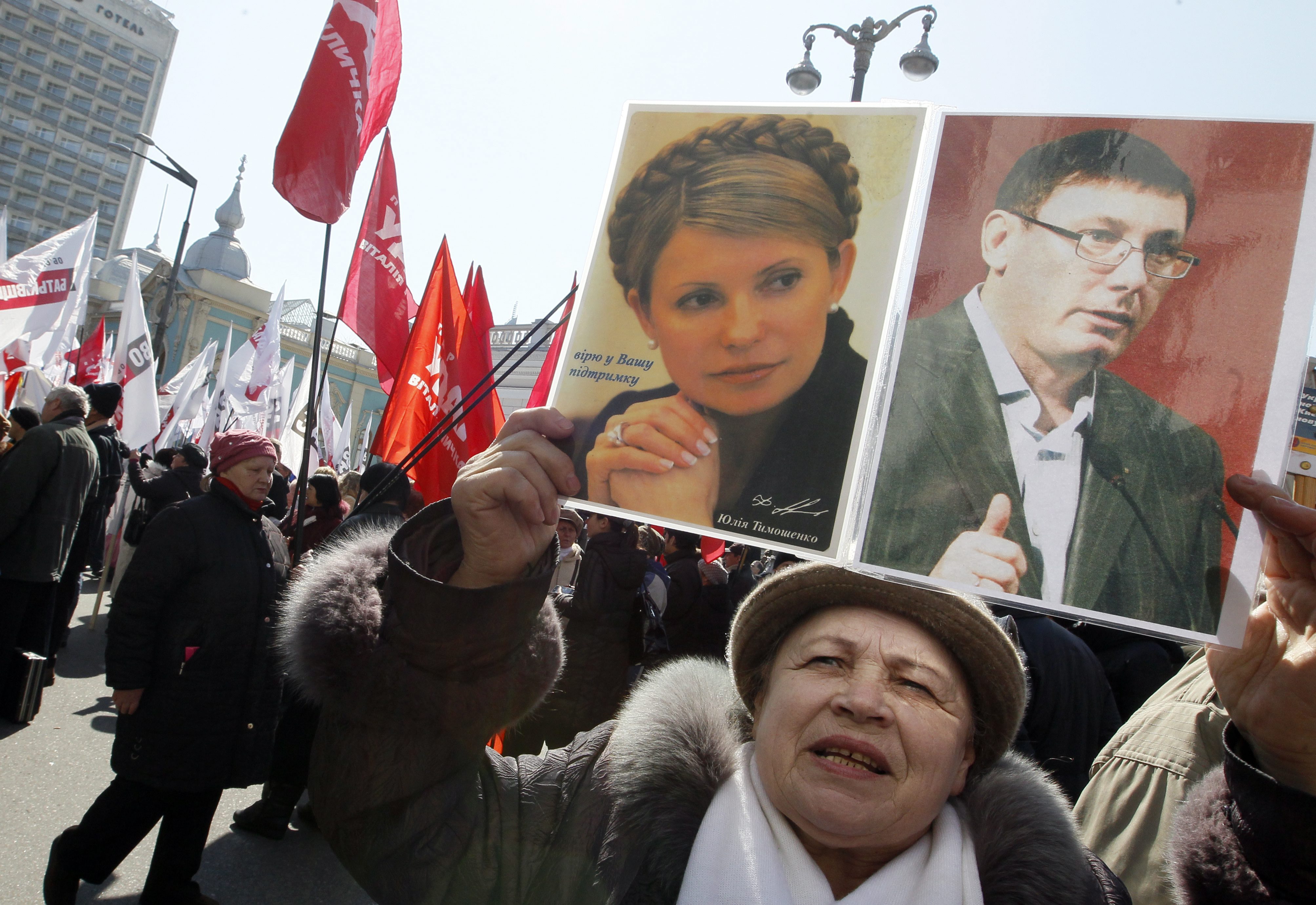 A Ukrainian opposition supporter waves portraits of their jailed leaders Yulia Tymoshenko (top left) and Yuriy Lutsenko during a rally near Parliament in Kiev. Photo: EPA