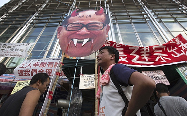 Striking dock workers stand in front of a defaced image of Li Ka-shing during a protest on Thursday. Photo: Reuters
