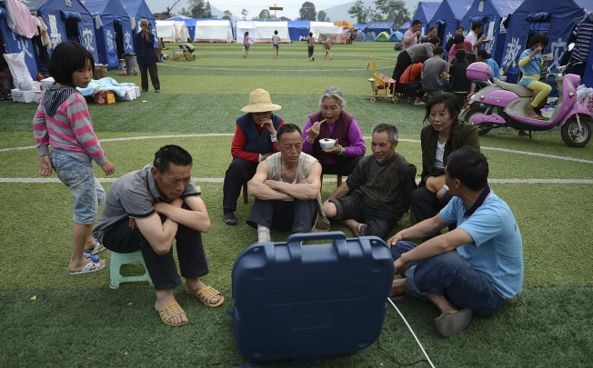 People displaced by the April 20 earthquake in Sichuan watch television near their tents in Lushan county's Longmen township. Photo: Reuters