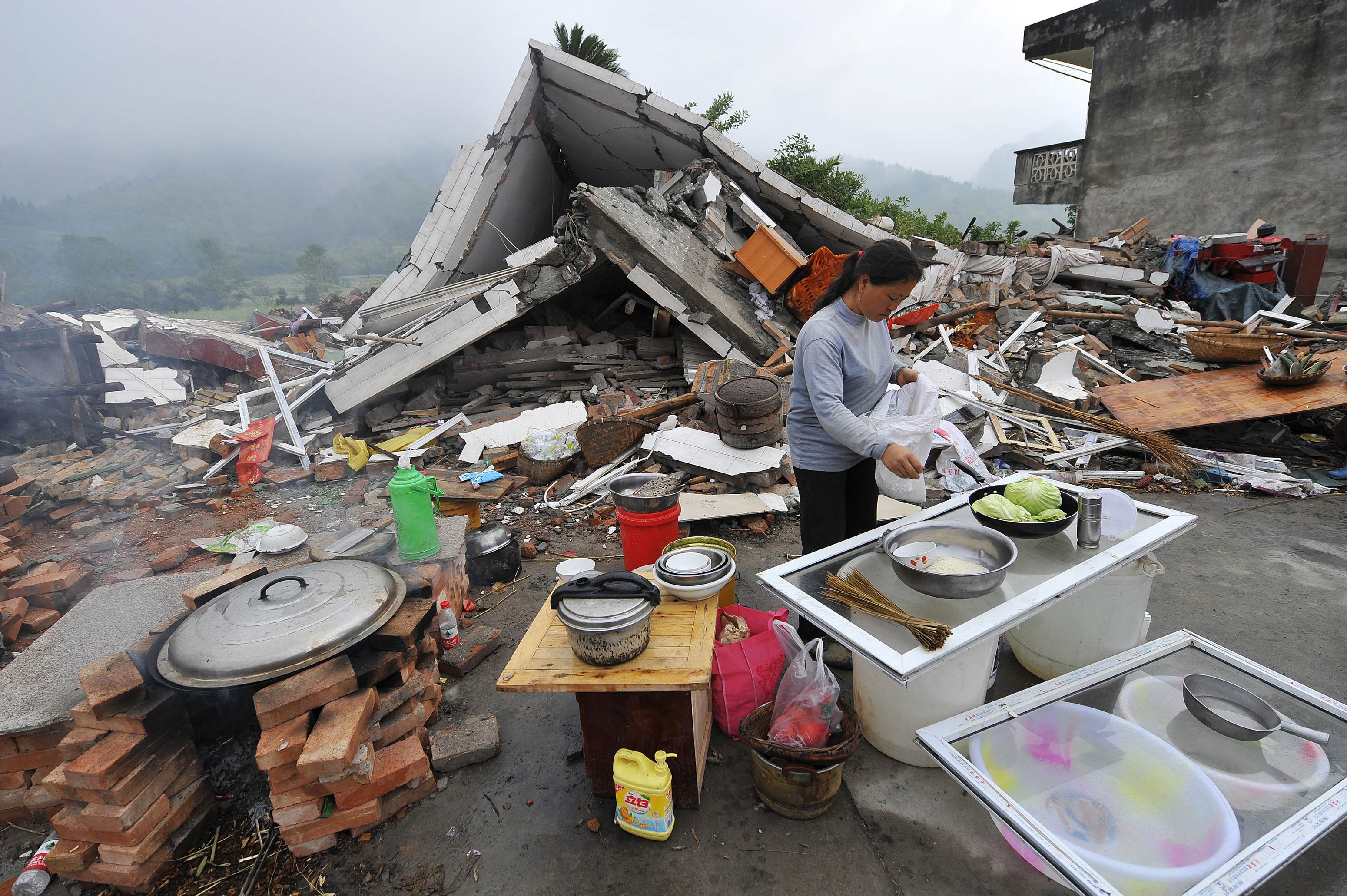 A woman cooks beside a collapsed house in Lushan county, Yaan, in southwest China's Sichuan province. Photo: AFP