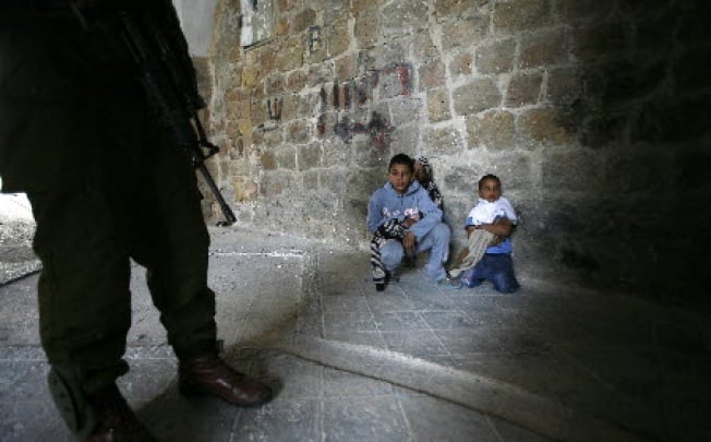 An Israeli soldier stands next to three Palestinian boys in the West Bank. While Israel may not face a third Palestinian intifada, the security situation in the West Bank still remains fragile. 