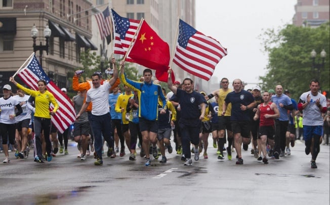 Runners carry flags as they approach the finish line after completing the final mile of marathon, cut short last month. Photo: Reuters