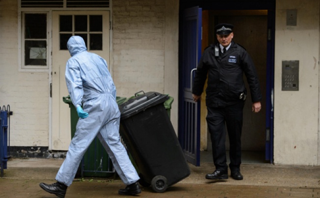 A forensics officer removes items from a flat where Michael Adebowale is registered as living. Photo: AP