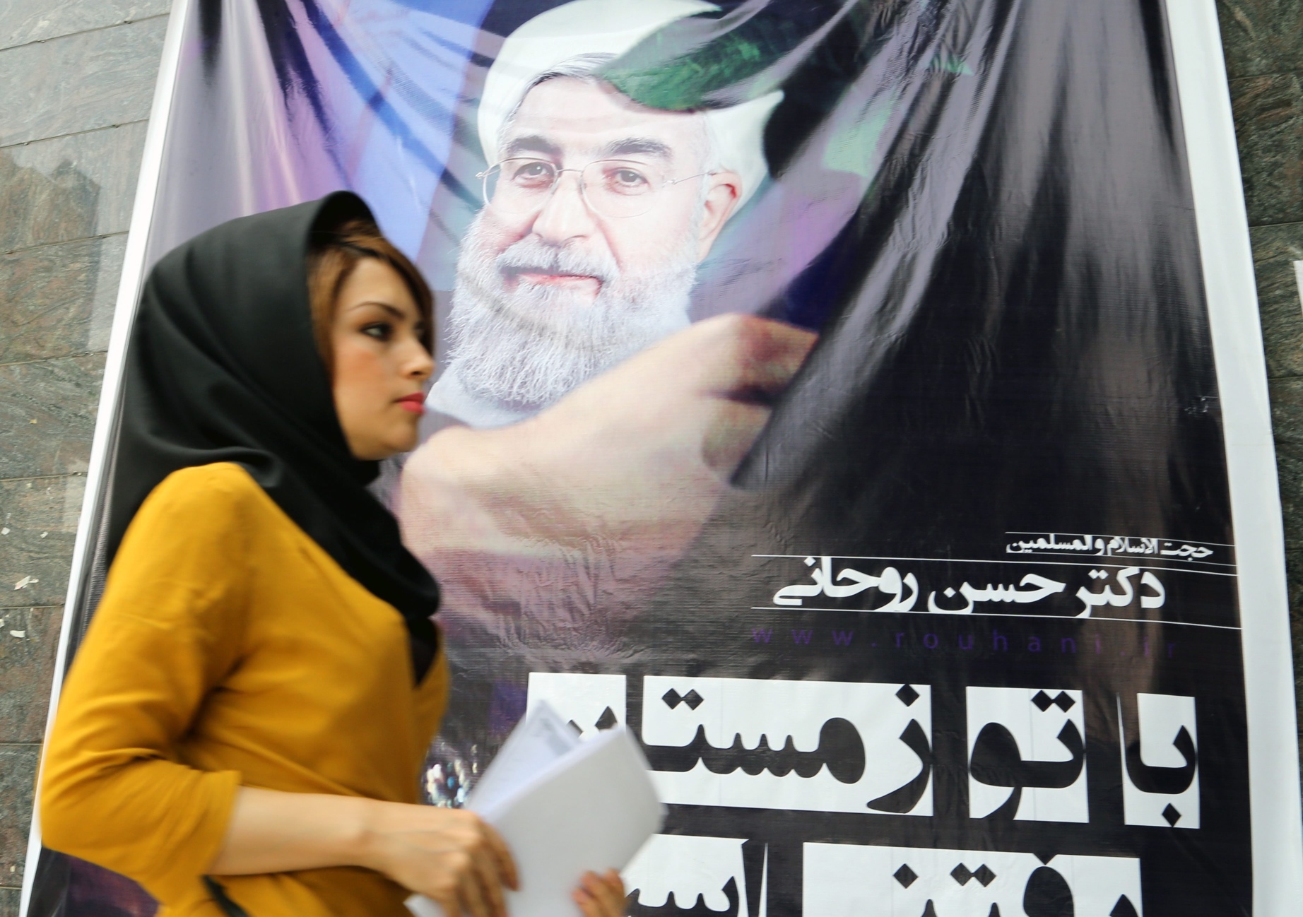 A young Iranian woman passes by a huge election poster of Iranian presidential candidate Hassan Rowhan for the upcoming June 14 for the upcoming election, in Tehran. Photo: EPA