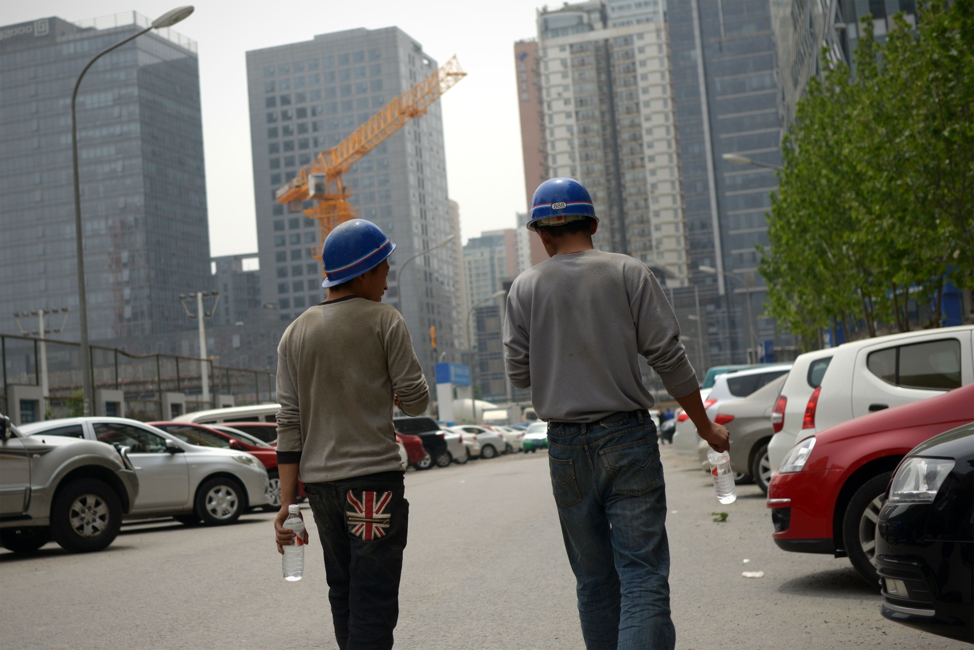 Two Chinese workers walk towards a construction site in Beijing. China plans to gradually begin easing applications and approval procedures for foreign investors. Photo: AFP 