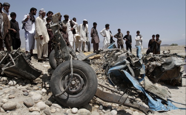 Afghans look at a destroyed vehicle after it was hit by a road side bomb in the Alingar district of Laghman province, east of Kabul, Afghanistan. Photo: AP