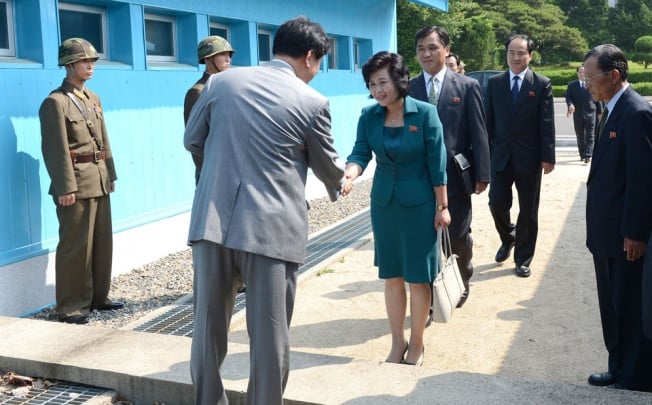 A South Korean official (front) shakes hands across the border with North Korean envoy Kim Song-hye at Panmunjom. Photo: Reuters