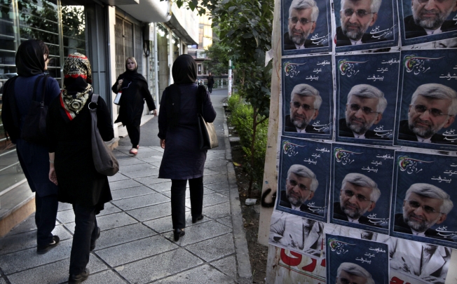 Iranian women walk past posters of presidential candidate Saeed Jalili a day prior to the election in Tehran. Photo: AP