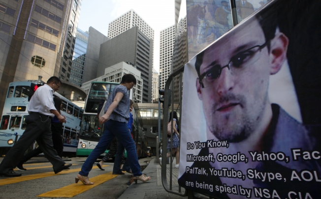 People walk past a banner supporting Edward Snowden at Central, Hong Kong's business district. Photo: AP