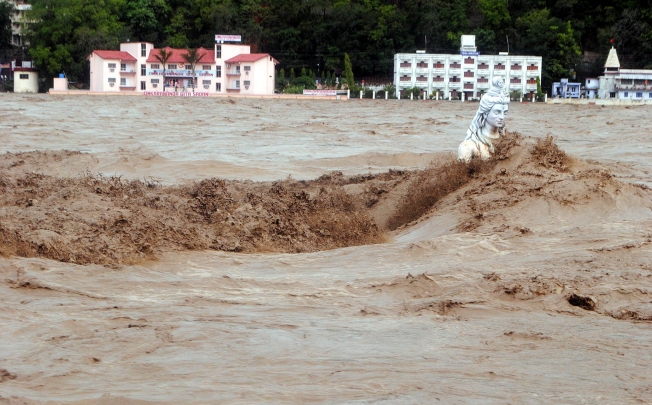 Fast moving water flows over a Hindu statue during a heavy monsoon rain in Rishikesh town in the Indian state of Uttrakhand. Photo: AFP