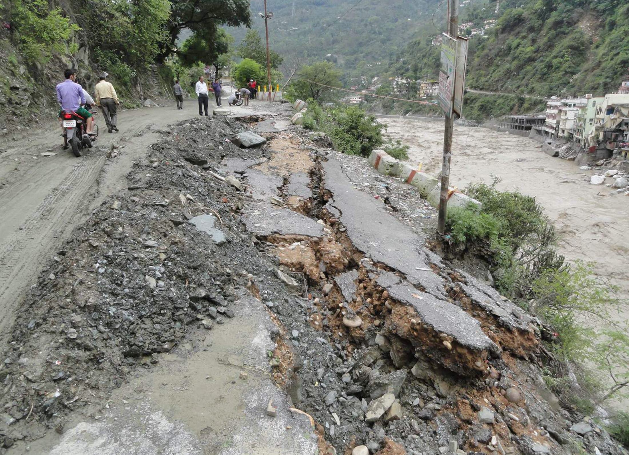 People walk along a damaged road after heavy rains in the Himalayan state of Uttarakhand. Thousands stranded in parts of northern India awaited rescuers. Photo: AFP