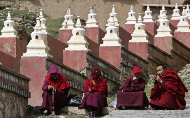 Monks sit at an entrance to the Dzamthang Jonang monastery, where a Tibetan woman set herself on fire. Photo: Reuters