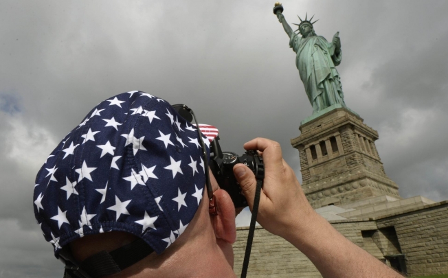 A visitor snaps a memento of the Statue of Liberty as it reopens to the public for the first time since Superstorm Sandy smashed into New York last October. Photo: AFP