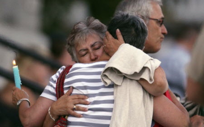 A woman consoles her friend during a vigil at Sainte-Agnes church in Lac-Megantic in Quebec. Transportation workers searched the site of the train derailment as police increased the number of confirmed killed by four to 28. Photo: Reuters
