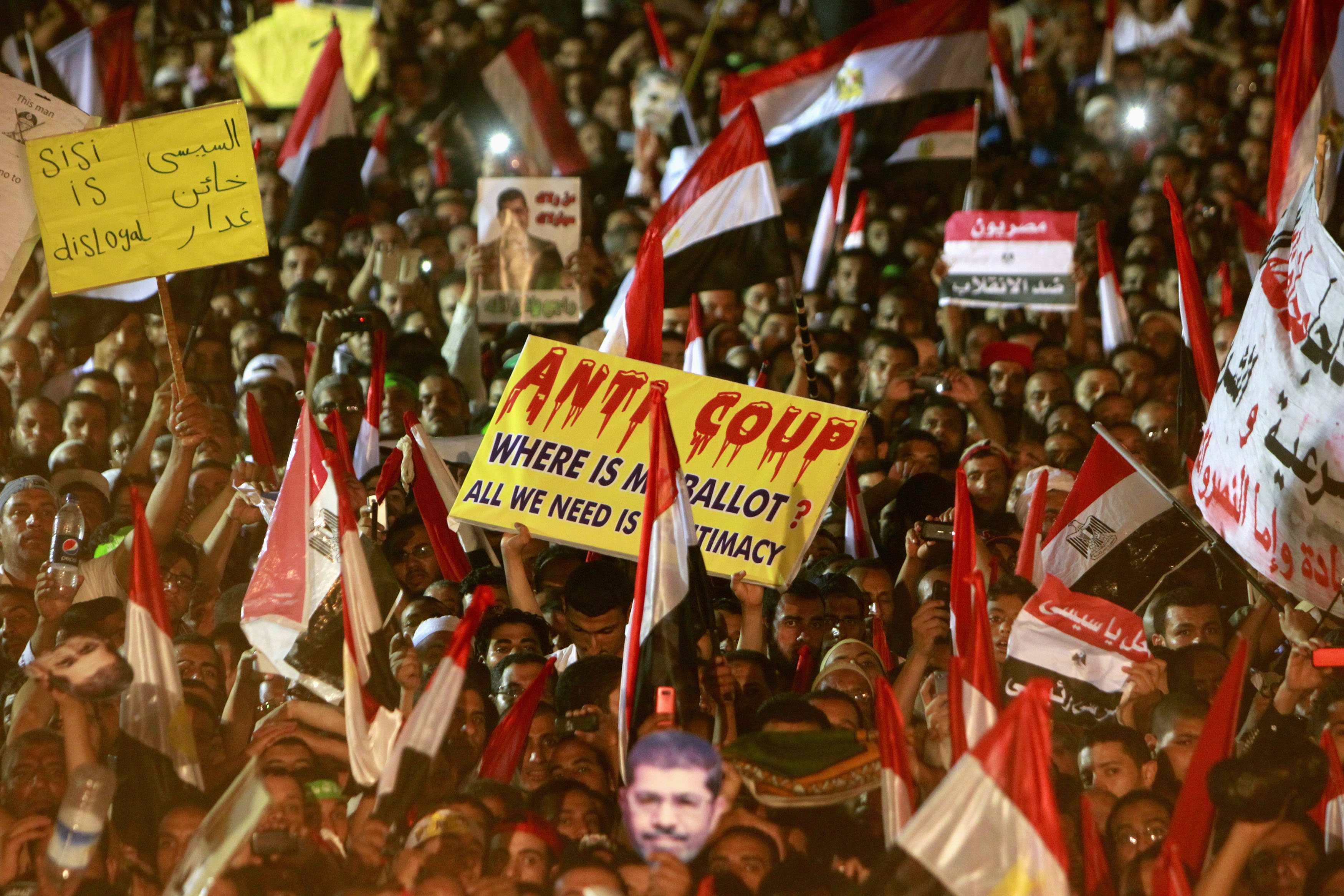 Members of the Muslim Brotherhood and supporters of deposed Egyptian President Mohammed Mursi wave Egyptian flags, signs and masks of him as they gather at the Rabaa Adawiya square  in Cairo, where they are camping. Photo: Reuters