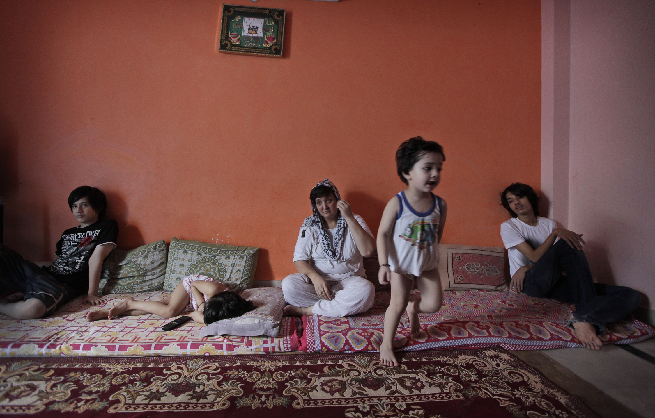 Two-year-old Hussain runs in the family's small flat as his mother Sharifa Jan, centre, and siblings sit on mattresses in Bhogal in New Delhi, India. Jan and her children fled Afghanistan for India last year. Photo: AP
