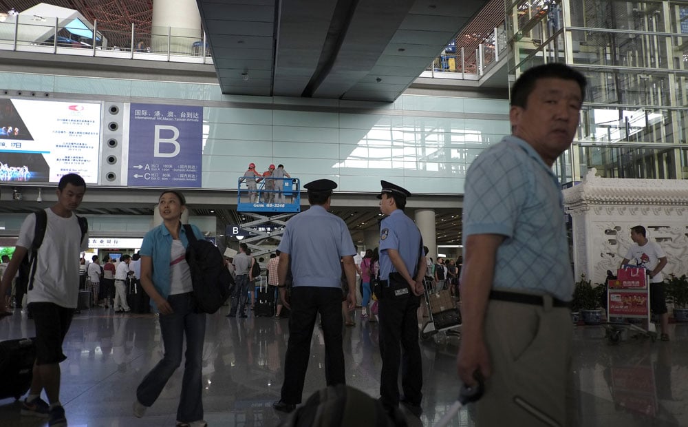Passengers walk past Chinese policemen stand watch at Terminal 3 international arrival hall of the Beijing Capital International Airport. Photo: AP