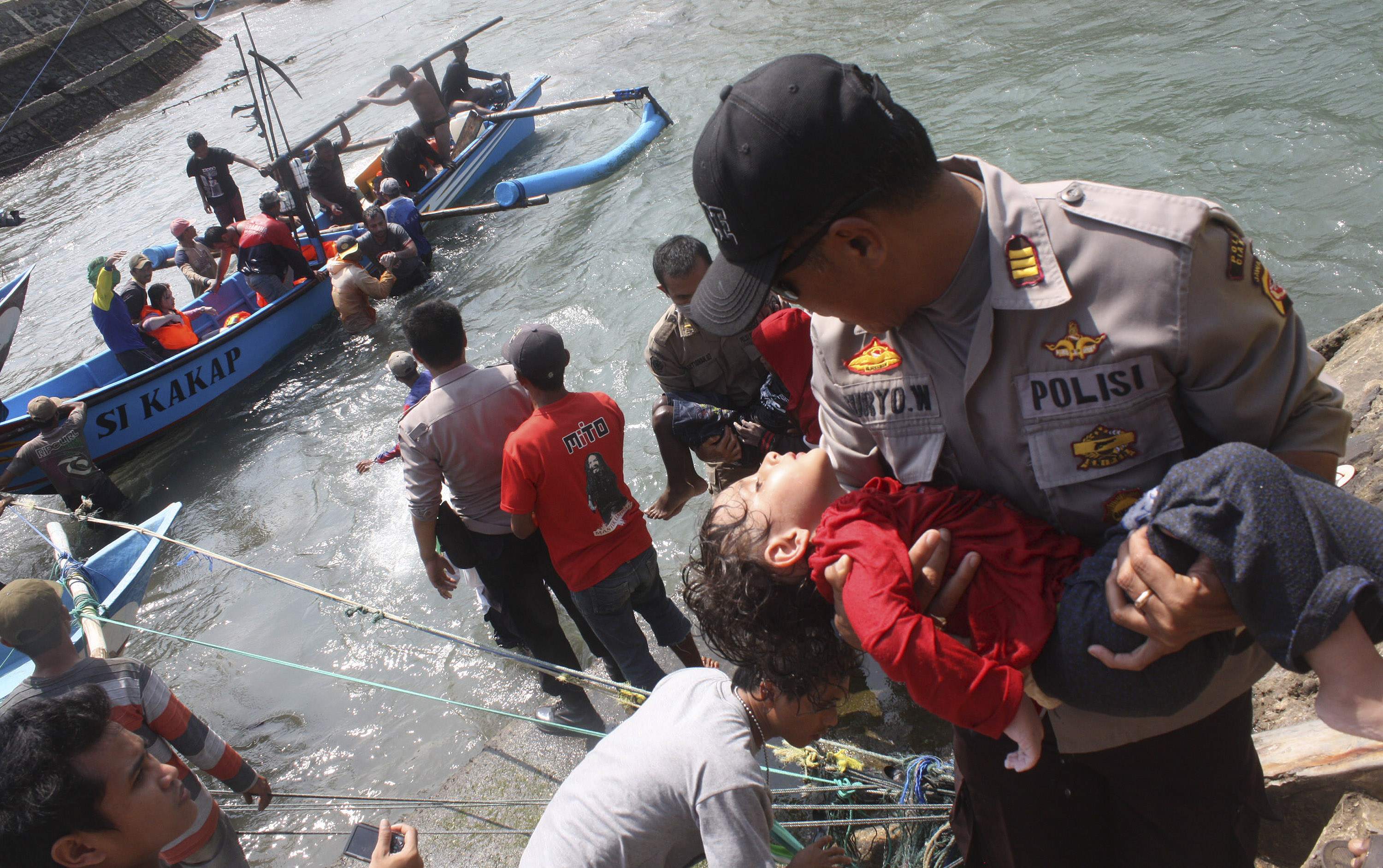 A police officer carries an unconscious child from the boat that capsized after hitting a reef off the coast of Sukapura, in Cianjur. Photo: Reuters