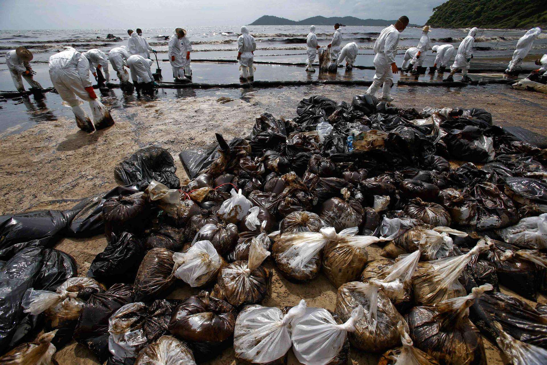 Soldiers in white biohazard suits work to contain the oil that has spilled onto Ao Prao beach on Koh Samet. Photo: Reuters