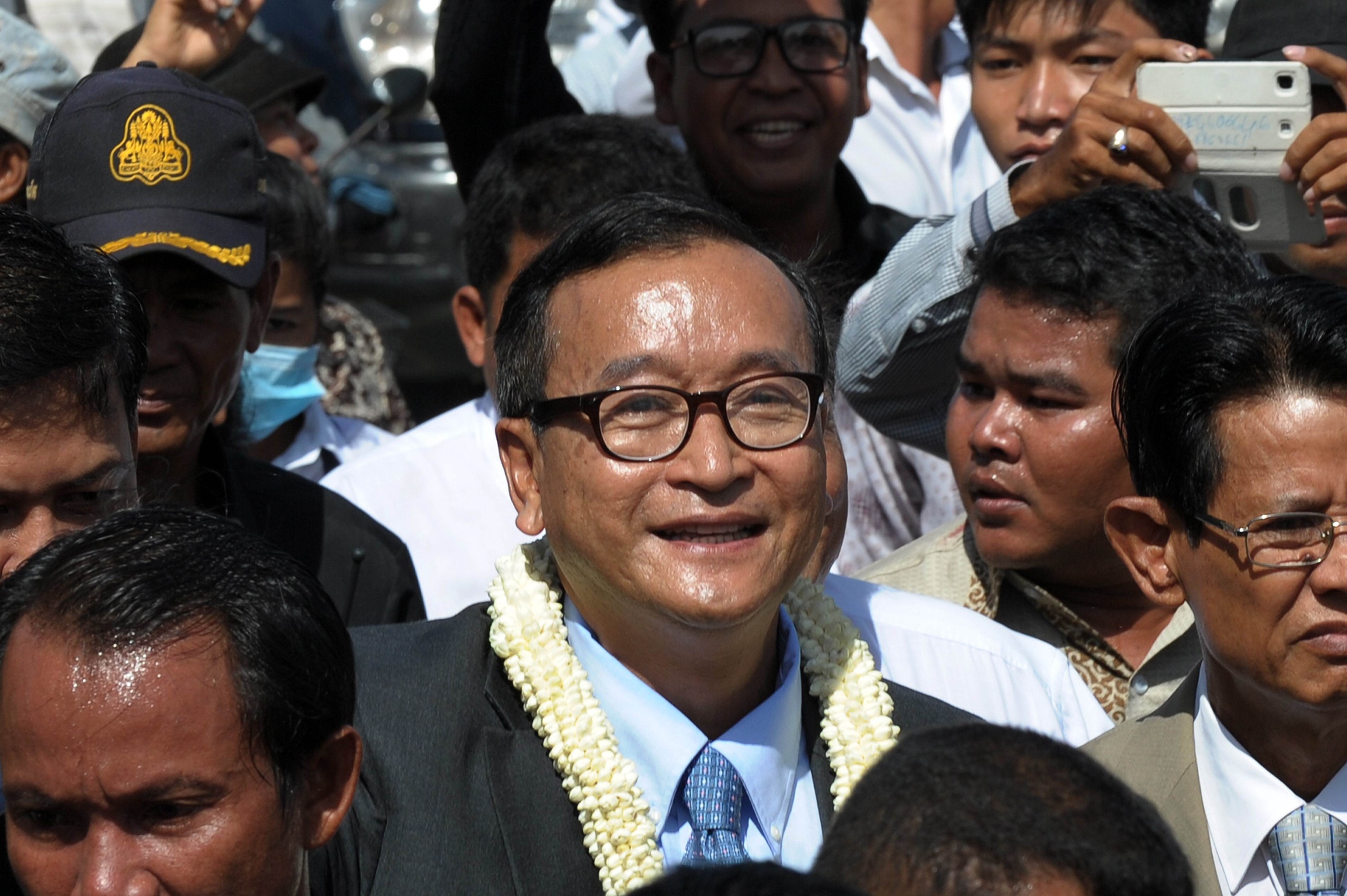Sam Rainsy (C), leader of the opposition Cambodia National Rescue Party (CNRP), smiles along a street in Phnom Penh on Friday. Photo: AFP