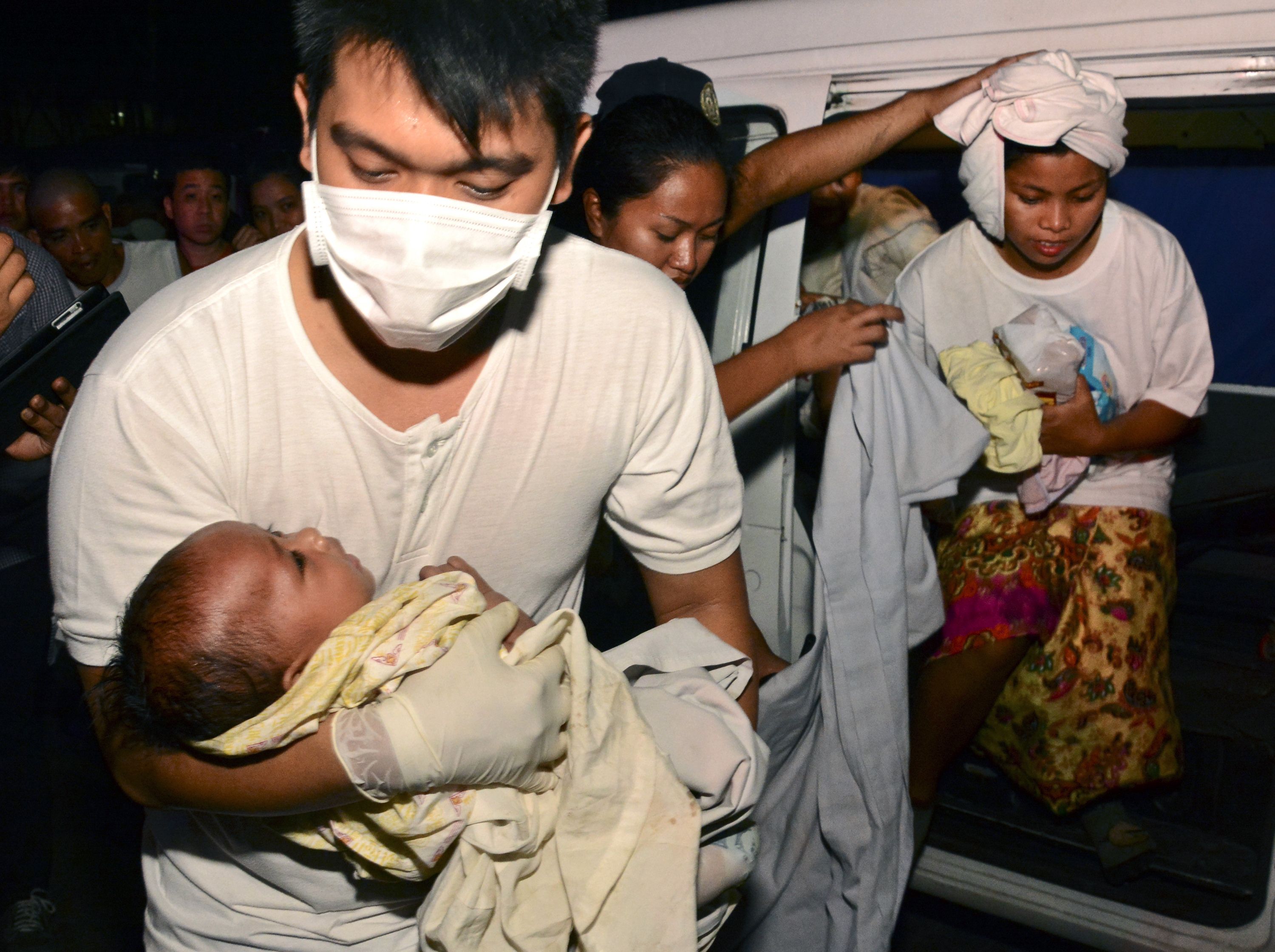 A medic carries rescued three-month old Trisia Mae Kumaro along with her mother (back) after they were rescued from a sea collision in Cebu. Photo: AFP