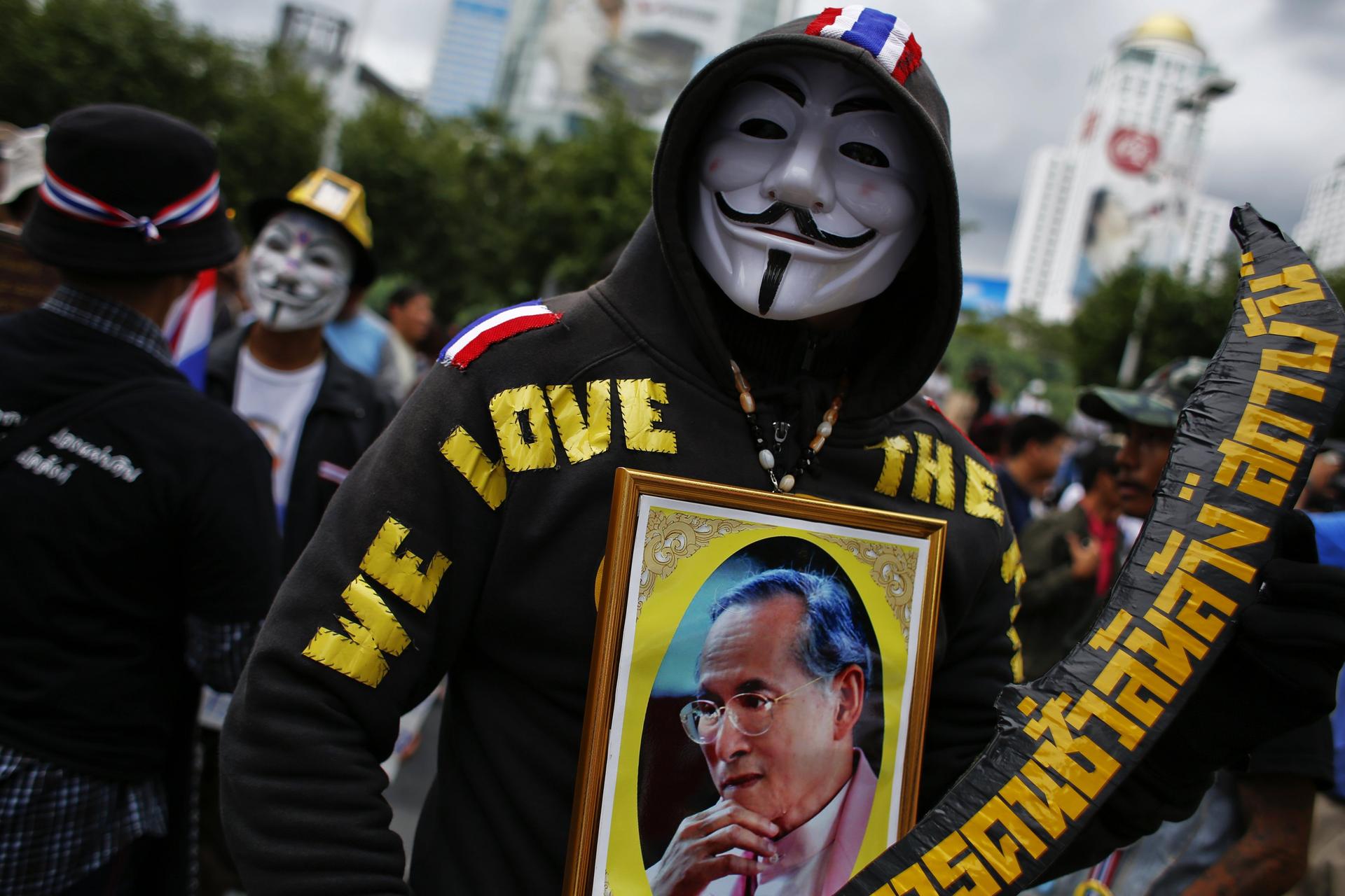 An anti-government protester wearing a Guy Fawkes mask holds a picture of Thai King Bhumibol Adulyadej during a march in Bangkok yesterday. Photo: Reuters