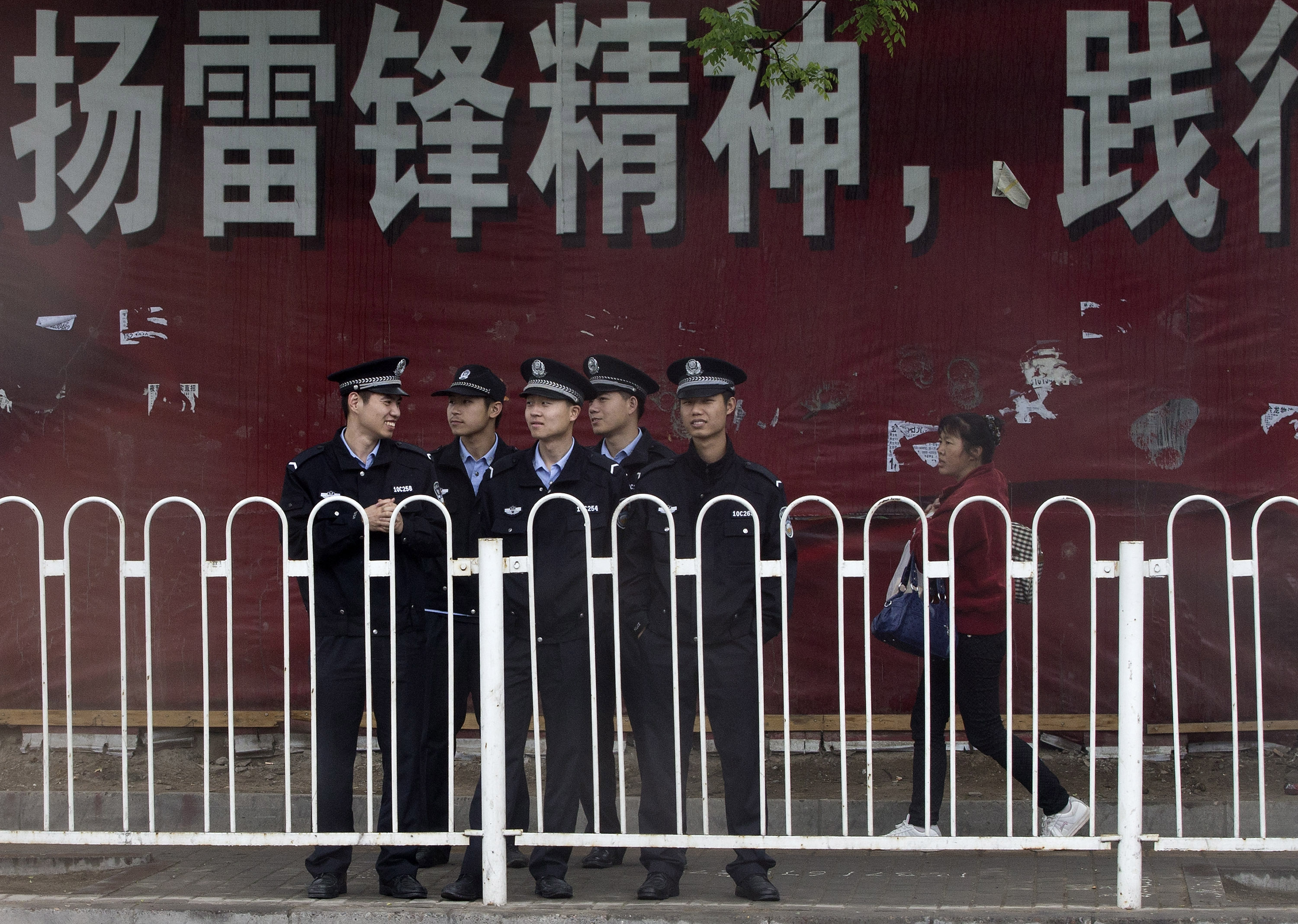 A Chinese woman walks by a troop of policemen near a clothing wholesale mall in Beijing. Photo: AP