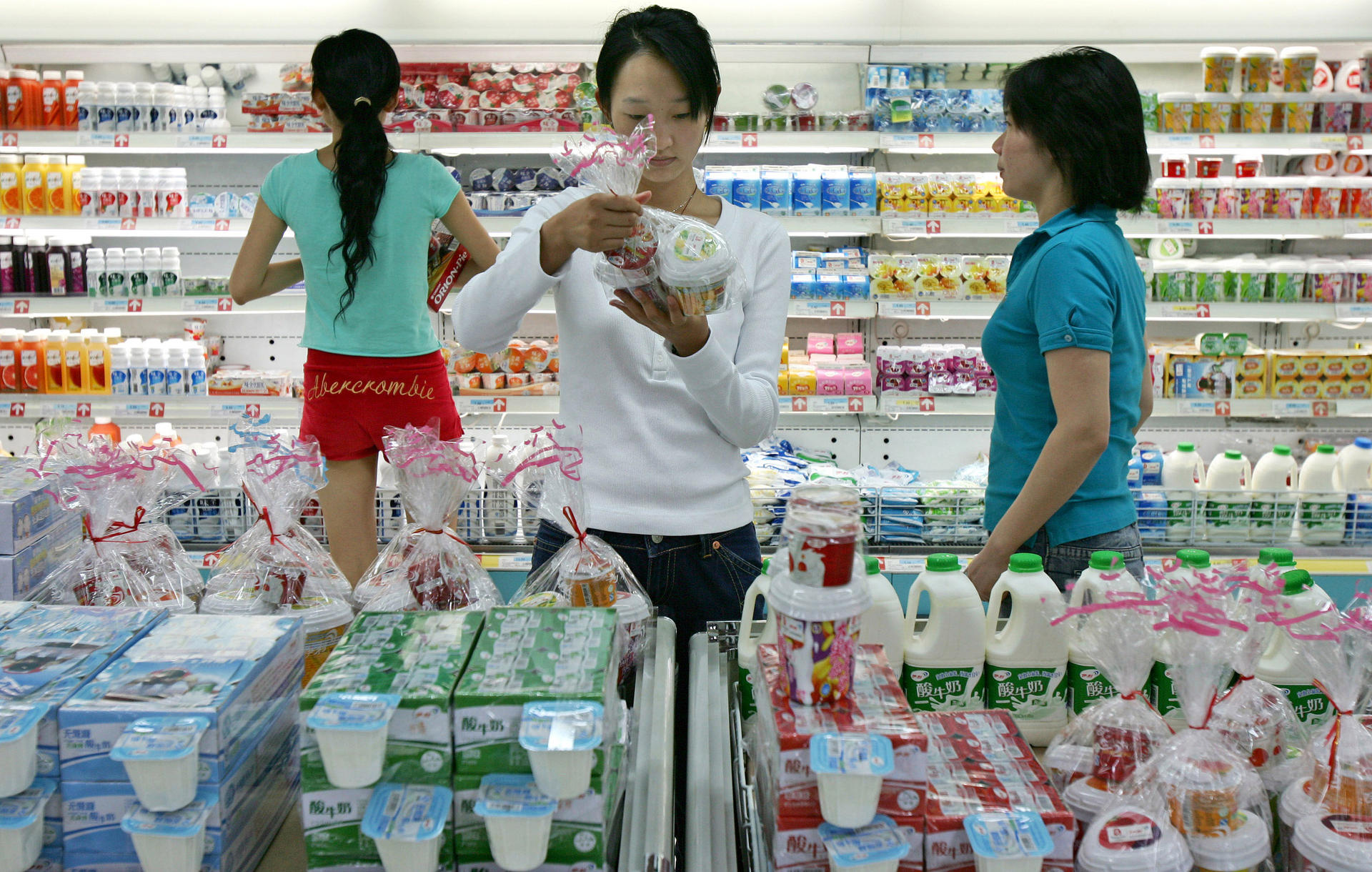 A Beijing shopper examines milk from China Mengniu Dairy, the main client for China Modern Dairy's raw milk. Photo: Bloomberg