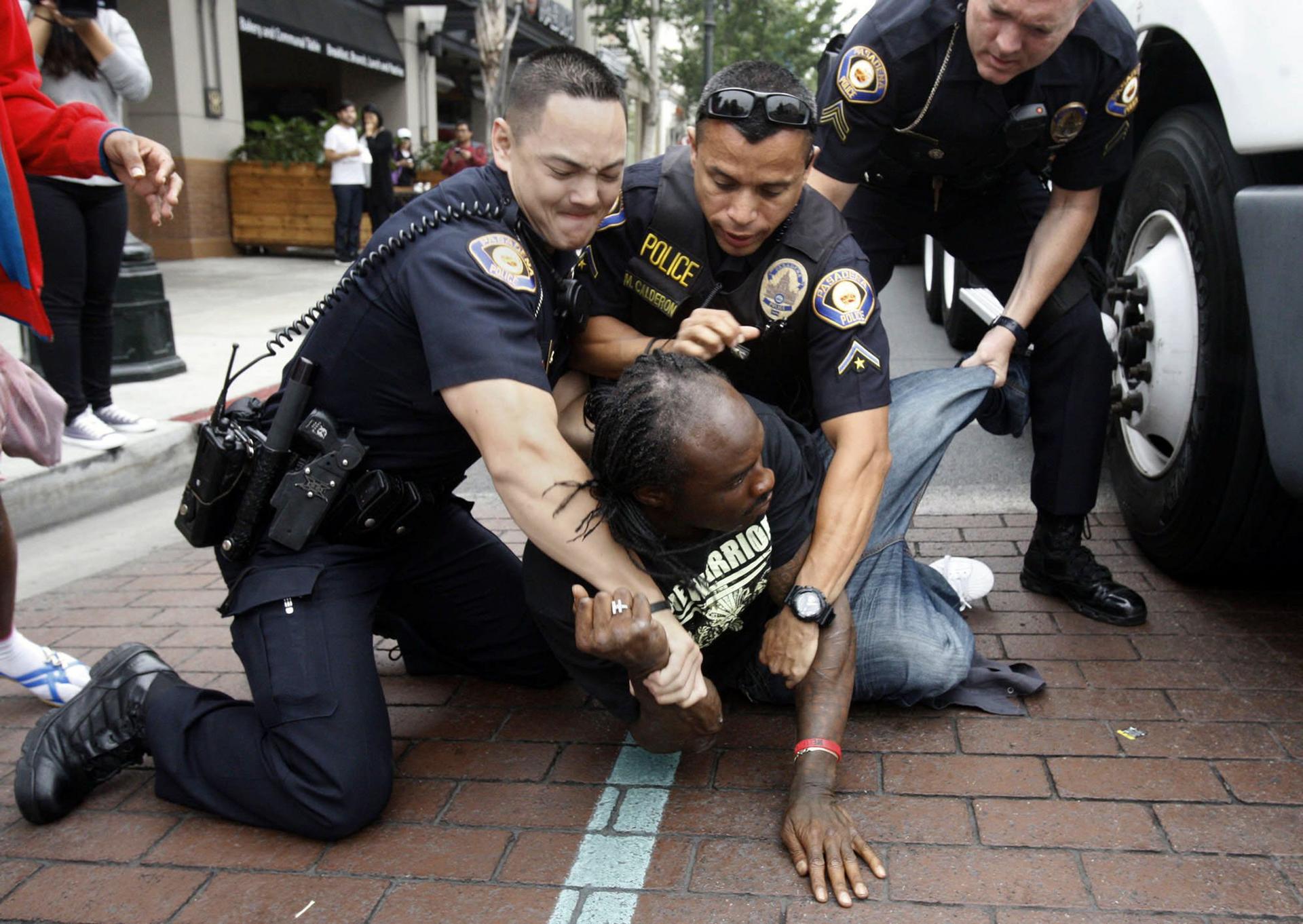 Pasadena police hold down a man who was upset when the deal fell through after he queued overnight for the coveted gadget. Photo: MCT